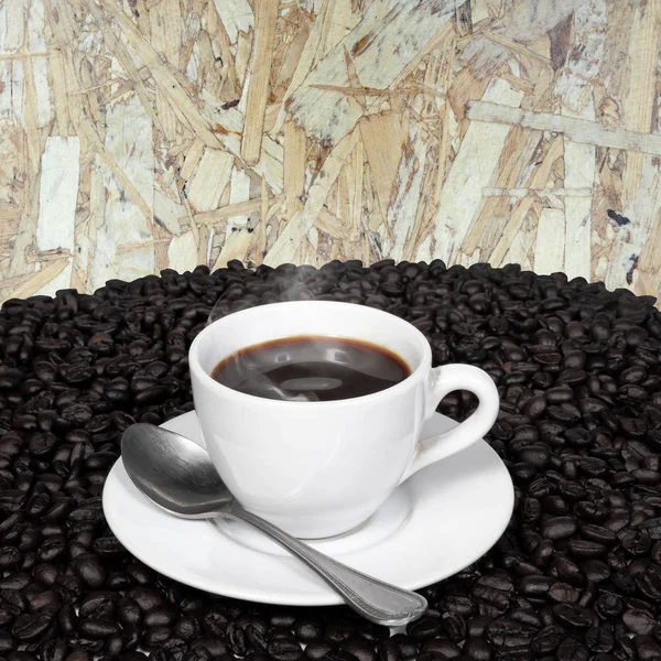 Café preto e grãos de café com fumaça na placa de madeira — Fotografia de Stock