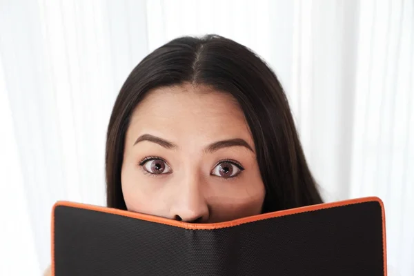 Jeune femme regarde dans les yeux écarquillés du livre noir — Photo