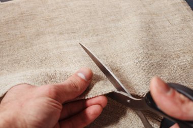 Bir adamın elini keten kumaş terzi makas ile keser..