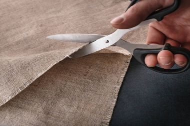 Bir adamın elini keten kumaş terzi makas ile keser..