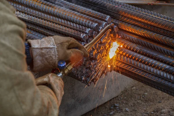 Gas cutting of metal fittings. Working gloves. Sparks.