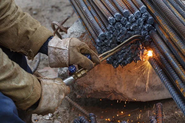 Gas cutting of metal fittings. Working gloves. Sparks.