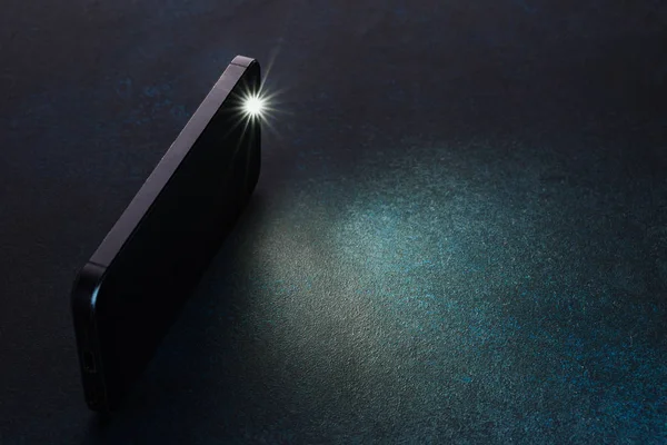 Lantern smartphone shines on a dark background. — Stock Photo, Image