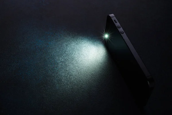 Lantern smartphone shines on a dark background. — Stock Photo, Image