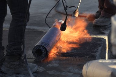 Laying of roofing felt from the roll with a flame from the burne clipart