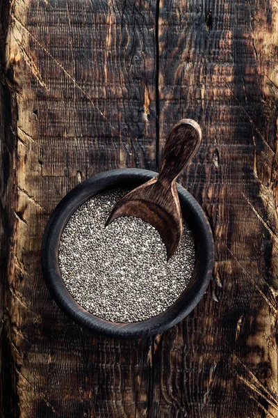 Semi di chia in una ciotola di legno su uno sfondo rustico di legno — Foto Stock