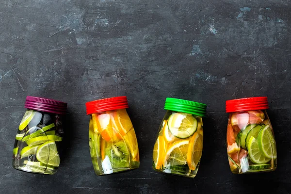 Verscheidenheid van de vruchten geïnfundeerd detox water in potten voor een gezonde voeding eten bovenaanzicht — Stockfoto