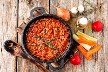 Kazan malzemelerle ahşap masa, üstten görünüm üzerinde demlenmiş klasik İtalyan bolognese sos