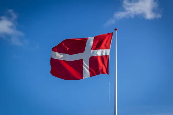 Bandeira dinamarquesa ao sol contra o céu azul com nuvens, horizontal — Fotografia de Stock