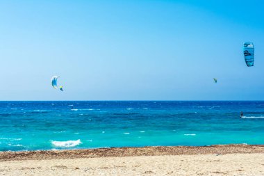 Yunanistan 'ın Lefkas adasındaki Agios Ioannis plajı. Renkli uçurtmalar uçurtma sörfçülerinden gökyüzüne kadar uzanıyor..