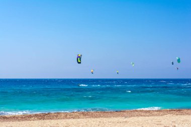 Yunanistan 'ın Lefkas adasındaki Agios Ioannis plajı. Renkli uçurtmalar uçurtma sörfçülerinden gökyüzüne kadar uzanıyor..