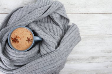 Gri yün atkı ya da ekoseye sarılı bir fincan baharatlı kahve. Sonbahar veya kış içeceği konsepti, Latte, cappuccino, Ekim, Kasım, anason