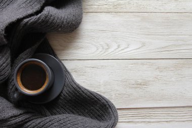 Ahşap beyaz masada gri kahve ve yün eşarp. Sıcak içecek konsepti. Kahve dükkanı, espresso, shot, nesne