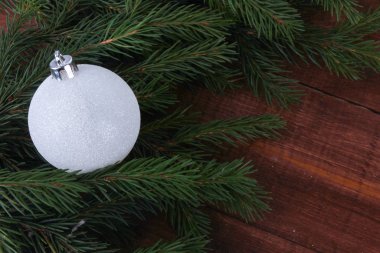 Köknar ağacı dallarına ve kahverengi ahşap masa üzerindeki beyaz takılara yakın çekim. Noel süsü. Yeni yıl, kış tatili, kopya alanı