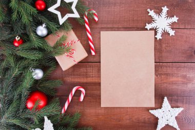 Noel mücevherleri, köknar ağacı dalları, hediye, şeker kamışı kahverengi ahşap masadaki yazı için kağıt. Noel kırsal arka planı. Yeni yıl, kış tatili, fotokopi alanı, üst manzara