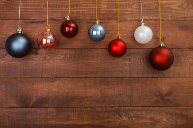 Ahşap, kahverengi duvarda asılı Noel mücevherleri. Yeni yıl ve Noel geçmişi kavramı. Boşluğu, topu, kar tanesini kopyala