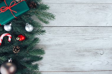 Kırmızı ve gümüş Noel mücevherleri, köknar ağacı dalları, hediye, beyaz ahşap masada şeker kamışı. Noel arkaplanı. Yeni yıl, kış tatili, fotokopi alanı, üst manzara