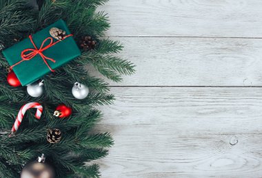 Kırmızı ve gümüş Noel mücevherleri, köknar ağacı dalları, hediye, beyaz ahşap masada şeker kamışı. Noel arkaplanı. Yeni yıl, kış tatili, fotokopi alanı, üst manzara