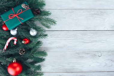 Kırmızı ve gümüş Noel mücevherleri, köknar ağacı dalları, hediye, beyaz ahşap masada şeker kamışı. Noel arkaplanı. Yeni yıl, kış tatili, fotokopi alanı, üst manzara