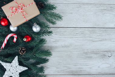 Kırmızı ve gümüş Noel mücevherleri, köknar ağacı dalları, hediye, beyaz ahşap masada şeker kamışı. Noel arkaplanı. Yeni yıl, kış tatili, fotokopi alanı, üst manzara