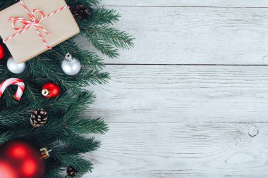 Kırmızı ve gümüş Noel mücevherleri, köknar ağacı dalları, hediye, beyaz ahşap masada şeker kamışı. Noel arkaplanı. Yeni yıl, kış tatili, fotokopi alanı, üst manzara