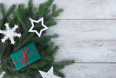 Beyaz Noel mücevherleri, köknar ağacı dalları, beyaz ahşap masadaki hediye kutusu. Noel arkaplanı. Yeni yıl, kış tatili, fotokopi alanı, üst manzara