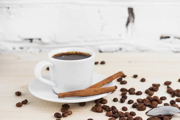 Una taza de café negro con canela y granos de café en una mesa de madera — Foto de Stock