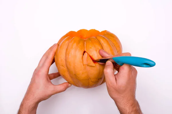 adam beyaz arka plan üzerinde şenlikli bir balkabağı fener yapar