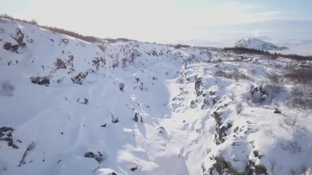 雪の上の飛行は アイスランドで冬岩谷を覆われている無人機します — ストック動画