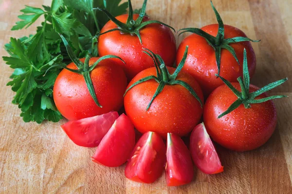 Deliciosos tomates vermelhos frescos com folhas de salsa em um fundo envelhecido de madeira — Fotografia de Stock