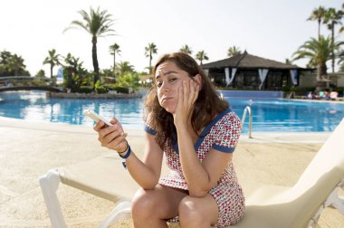 Attractive woman with phone by pool clipart
