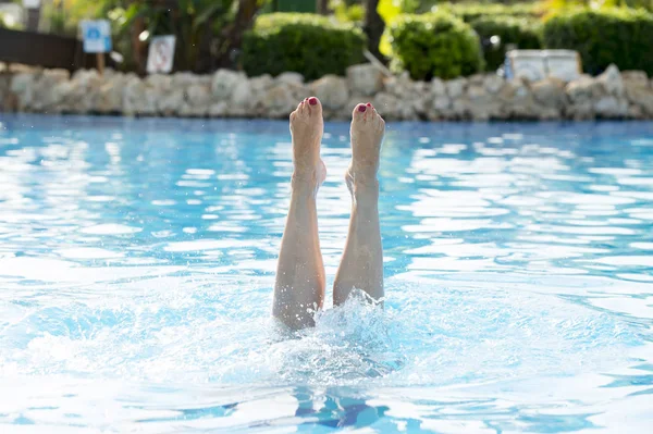 Pies femeninos salpicando fuera del agua — Foto de Stock