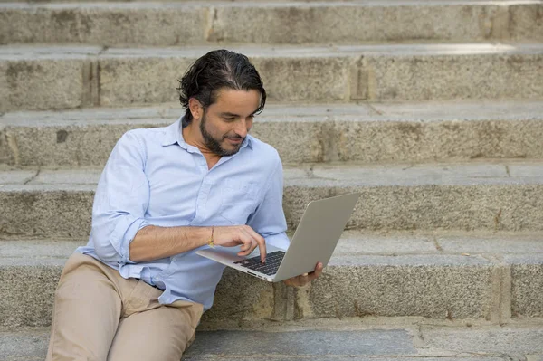Человек на городской лестнице работает с ноутбуком — стоковое фото