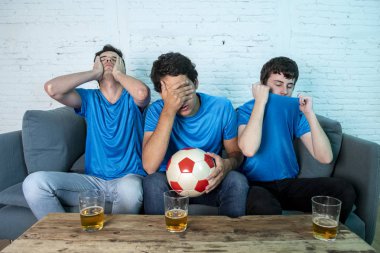 Mavi t-shirt futbol oyunu evde kanepede izlerken hayal kırıklığı genç futbol hayranları grup