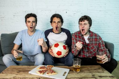 Grup genç futbol hayranları kanepe izlerken futbol oyun ve içki bira üzerinde oturan heyecanlı