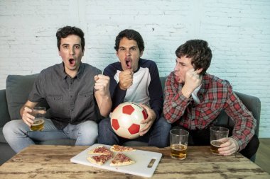 Grup genç futbol hayranları kanepe izlerken futbol oyun ve içki bira üzerinde oturan heyecanlı