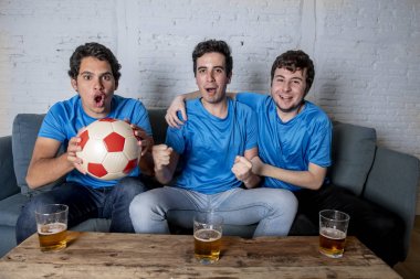 Grup genç futbol hayranları kanepe izlerken futbol oyun ve içki bira üzerinde oturan heyecanlı