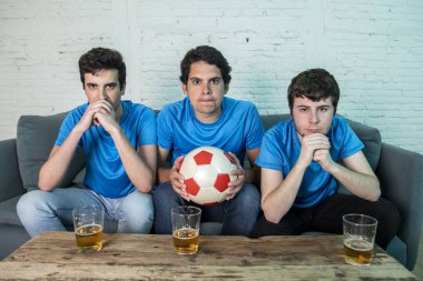 Mavi t-shirt futbol oyunu evde kanepede izlerken hayal kırıklığı genç futbol hayranları grup