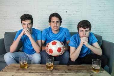 Mavi t-shirt futbol oyunu evde kanepede izlerken hayal kırıklığı genç futbol hayranları grup