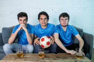 Mavi t-shirt futbol oyunu evde kanepede izlerken hayal kırıklığı genç futbol hayranları grup