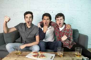 Grup genç futbol hayranları kanepe izlerken futbol oyun ve içki bira üzerinde oturan heyecanlı