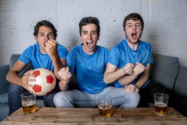 Grup genç futbol hayranları kanepe izlerken futbol oyun ve içki bira üzerinde oturan heyecanlı