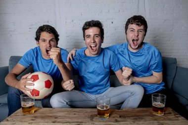 Grup genç futbol hayranları kanepe izlerken futbol oyun ve içki bira üzerinde oturan heyecanlı
