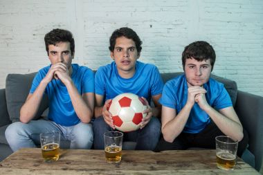 Mavi t-shirt futbol oyunu evde kanepede izlerken hayal kırıklığı genç futbol hayranları grup