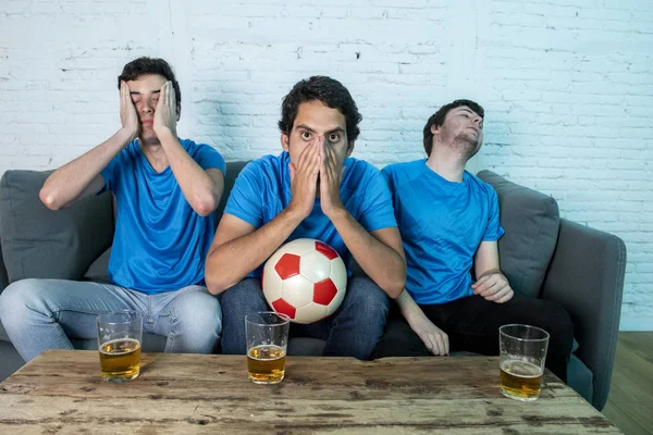 Mavi t-shirt futbol oyunu evde kanepede izlerken hayal kırıklığı genç futbol hayranları grup