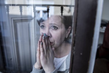 young beautiful depressed unhappy caucasian woman looking worried and sad through the window at home. feeling worthless and in pain. closeup. Depression and crisis concept clipart