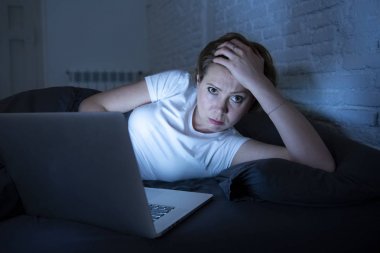 genç güzel, beyaz, kırmızı saçlı, kadın çalışma ve yatak odasında yatakta Onun laptopunda gecenin karanlık odada sıkılmış, uykusuz ve yorgun sörf internet bağımlısı. uykusuzluk.