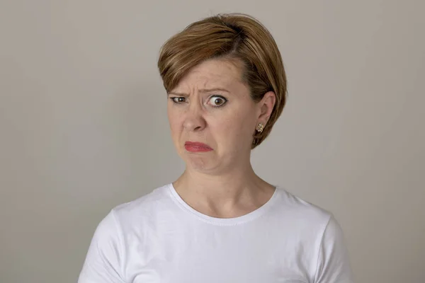 Close up beautiful young red haired caucasian woman with a disgusted expression. feeling dislike or disapproval of something. Human facial expressions and emotions.Gray background