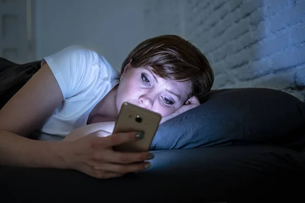 夜遅く暗い寝室のベッドで横になっているスマート フォンを使用して目を覚まし若い魅力的な女性 チャット インターネット中毒 モバイル虐待や不眠症概念でメッセージを送信する携帯電話を使用してください — ストック写真