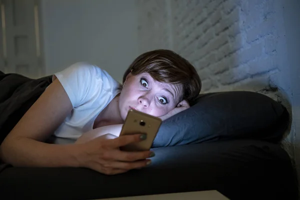 夜遅く暗い寝室のベッドで横になっているスマート フォンを使用して目を覚まし若い魅力的な女性 ショックを受け 眠れないを探しています 不眠症の概念 モバイル虐待の常習インターネット電話を使用してください — ストック写真